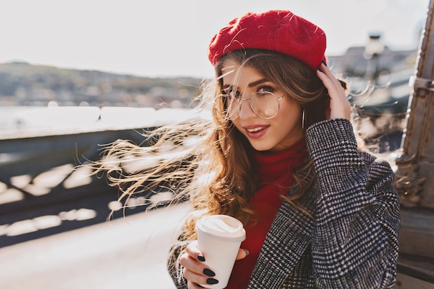 Free photo beautiful girl with big blue eyes posing on the street in cold windy day with cup of coffee