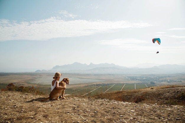 Free photo beautiful girl with and dog on the mountain top