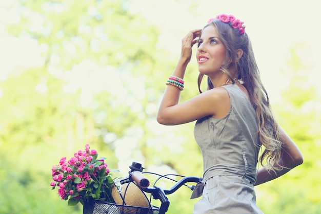 Free photo beautiful girl with flowers on a bike