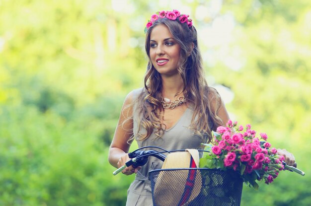 Beautiful girl with flowers on a bike