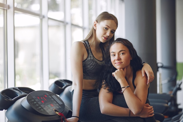 Free photo beautiful girls in a gym. sports ladies in a sportswear. friends training