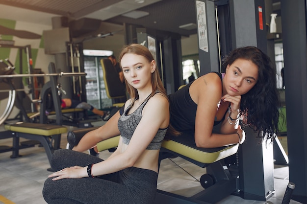 Free photo beautiful girls in a gym. sports ladies in a sportswear. friends training