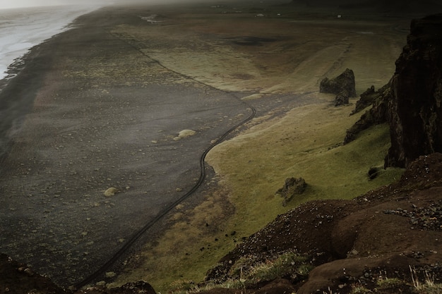 Free photo beautiful green land with hills by the sea on a foggy day