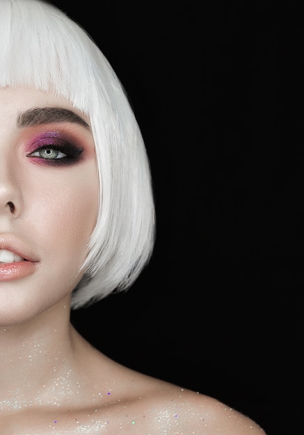 Beautiful half face woman looks to the camera isolated on black background.