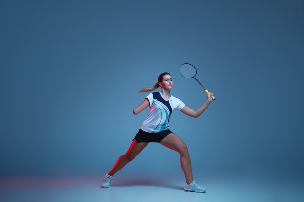 Beautiful handicap woman practicing in badminton isolated on blue background in neon light. Lifestyle of inclusive people, diversity and equility. Sport, activity and movement. Copyspace for ad.