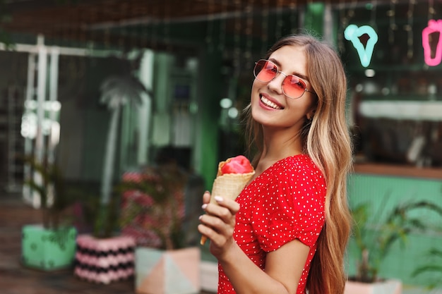 Beautiful hipster girl in sunglasses eating ice cream and smiling