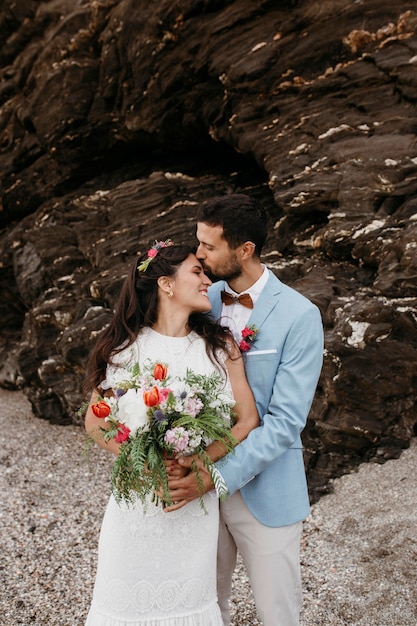 Free photo beautiful husband and wife posing on the beach at their wedding