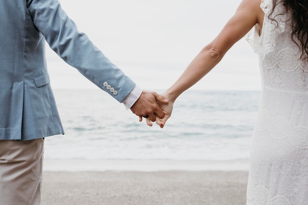 Beautiful husband and wife posing on the beach at their wedding