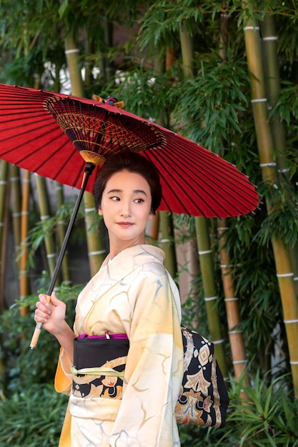 Free photo beautiful japanese woman with a red umbrella outdoors