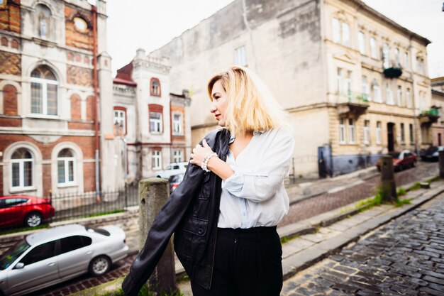 The beautiful lady keeping a jacket and standing on the street