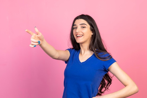 Beautiful lady pointing her finger aside and smiling for the camera High quality photo