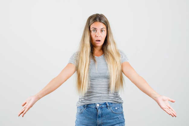 Beautiful lady showing helpless gesture in t-shirt , front view.