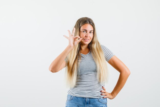 Beautiful lady showing ok gesture in t-shirt and looking joyful. front view.