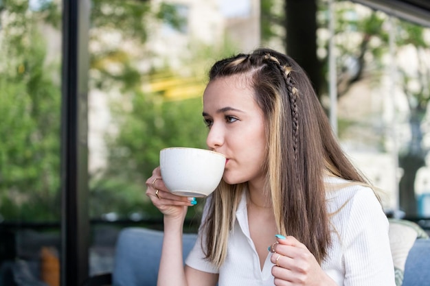 Beautiful lady sitting at the restaurant and drinking coffee