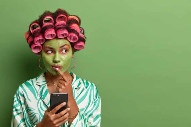 Beautiful lady wearing mask for face care wearing hair curlers isolated