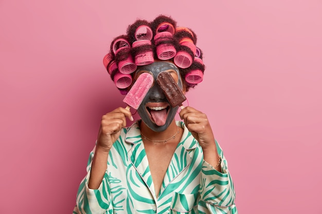 Beautiful lady wearing mask for face care wearing hair curlers isolated