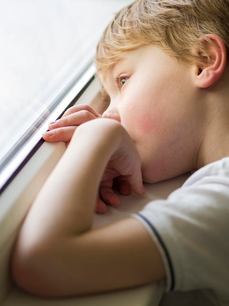 Beautiful little boy looking on window