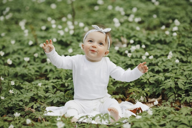 Free photo beautiful little girl rejoices in the forest among the flowers