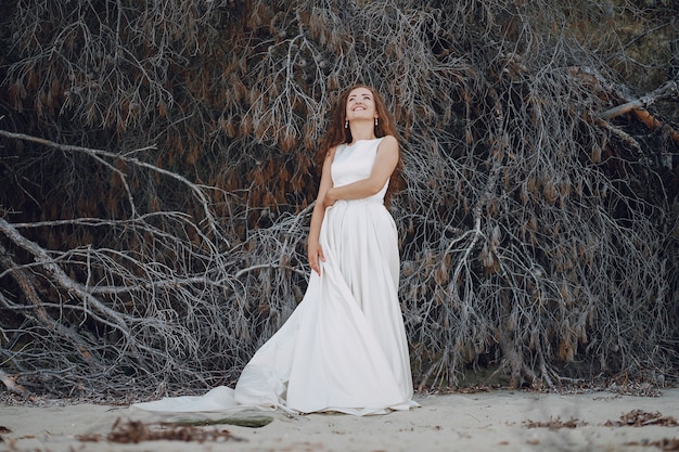 Beautiful long-haired bride in a magnificent white dress in nature