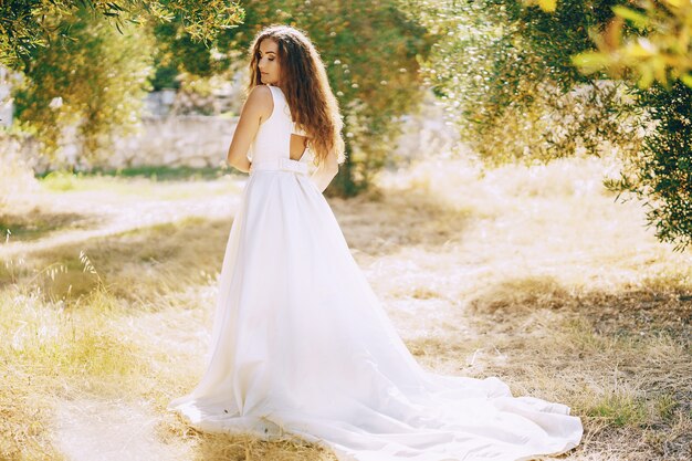 Beautiful long-haired bride in a magnificent white dress walking in nature