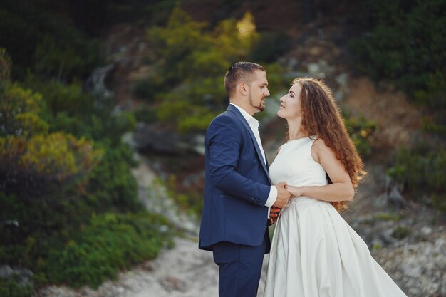 beautiful long-haired bride in white dress with her young man walking in the nature