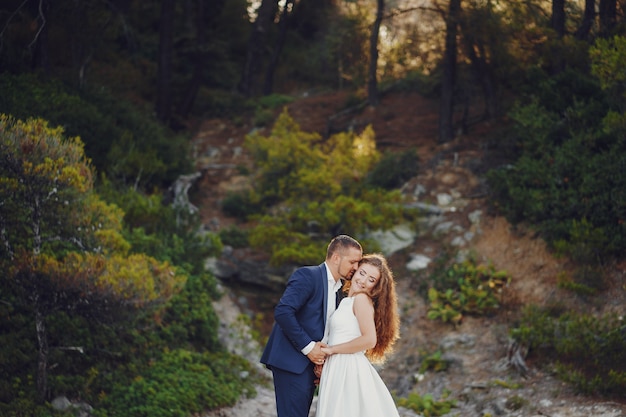 beautiful long-haired bride in white dress with her young man walking in the nature