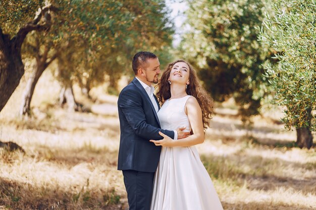 beautiful long-haired bride in white dress with her young man walking in the nature