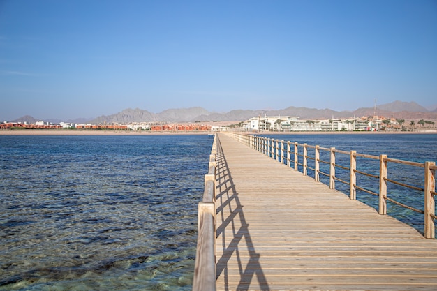 beautiful long wooden pier among the ocean and mountains.