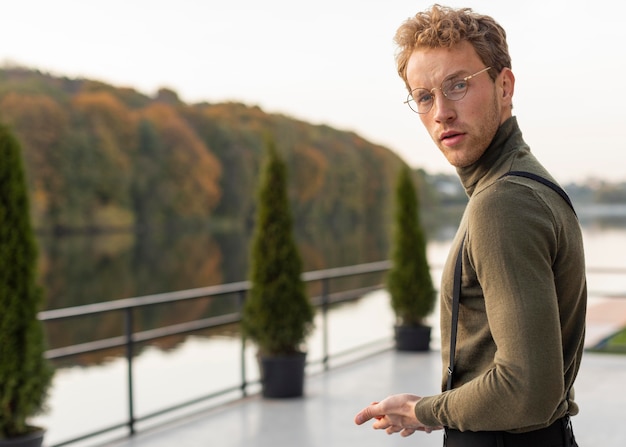 Free Photo beautiful male model standing next to a lake