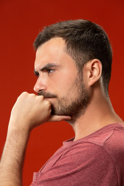 Beautiful man looking suprised and bewildered isolated on red