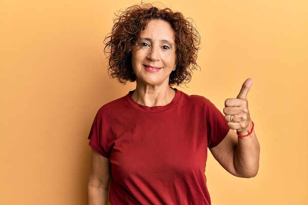 Beautiful middle age mature woman wearing casual clothes smiling happy and positive thumb up doing excellent and approval sign