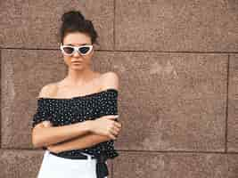 Free photo beautiful model dressed in elegant summer clothes.sexy carefree girl posing in the street near wall.trendy modern businesswoman in sunglasses having fun