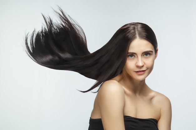 Free photo beautiful model with long smooth, flying brunette hair isolated on white studio background.