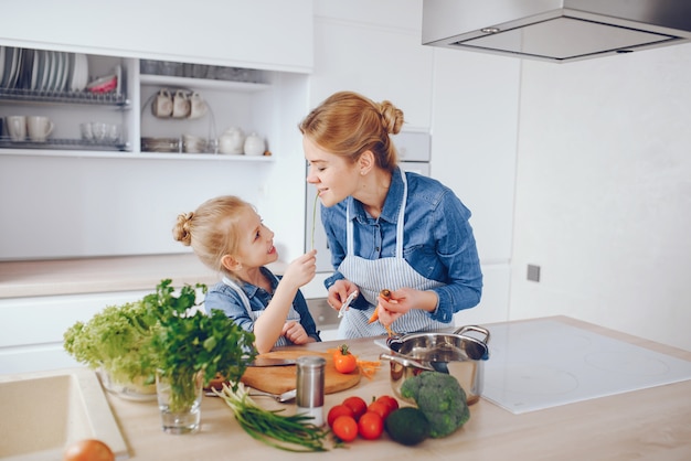 beautiful mother in a blue shirt and apron is preparing a fresh vegetable salad at home 