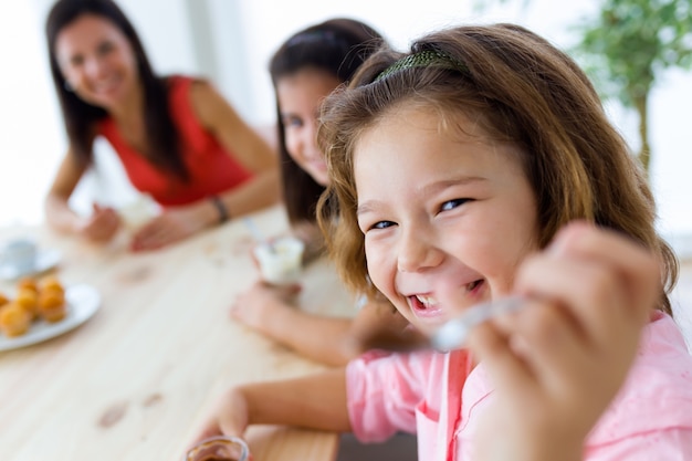 Free photo beautiful mother and her daughter eating iogurt at home.