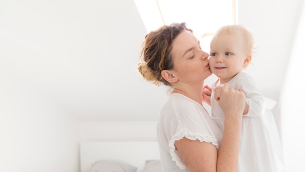 Beautiful mother kissing baby girl