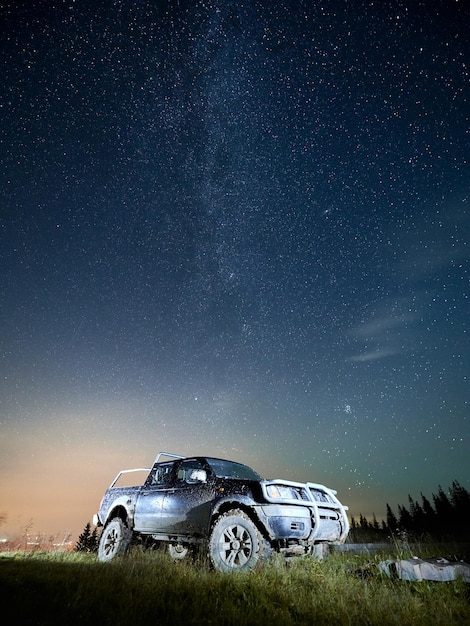 Free photo beautiful night starry sky over grassy hill with car