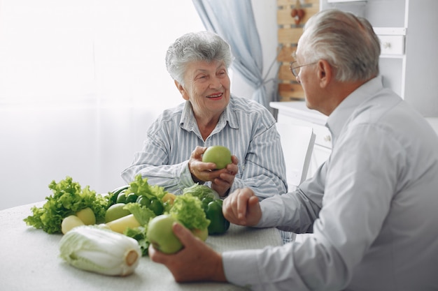 Beautiful old couple prepare food in a kitchen