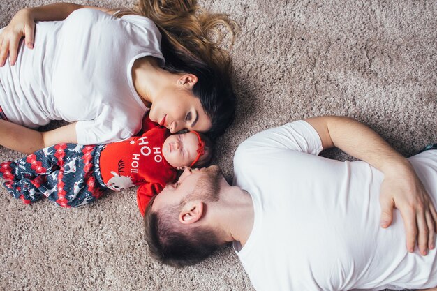 The beautiful parents with daughter liing on the floor