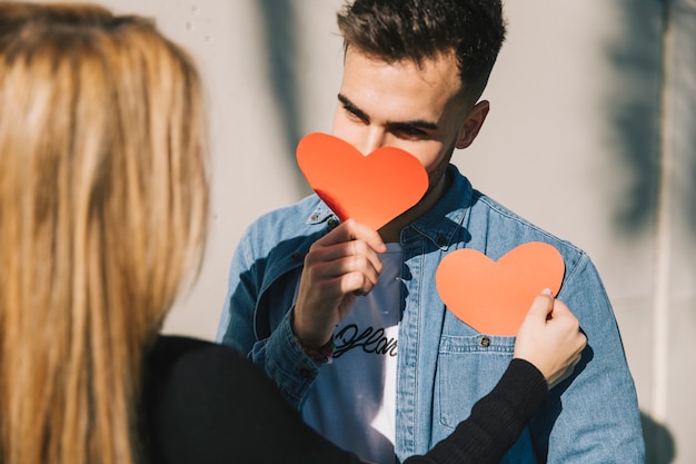 Free photo beautiful playful couple with paper hearts