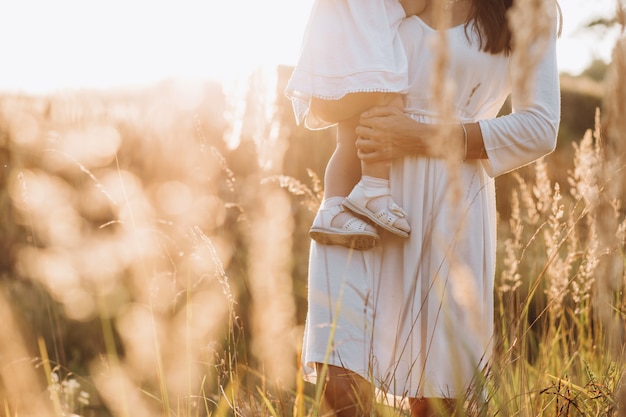 Beautiful portrait of charming mother and lovely little daughter walking across the field 