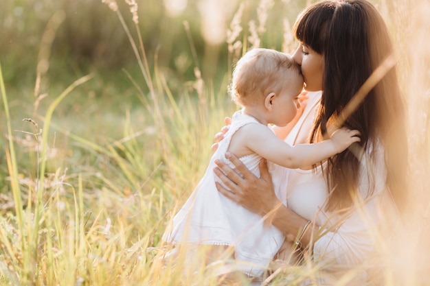 Beautiful portrait of charming mother and lovely little daughter walking across the field 