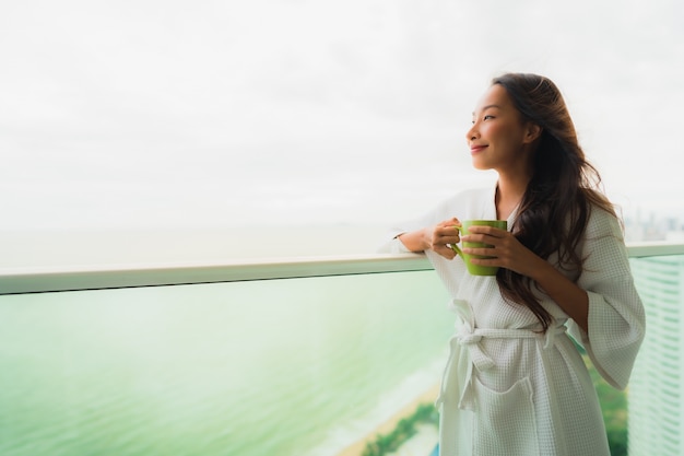 Beautiful Portrait young asian women holding coffee cup at outdoor balcony with sea ocean view