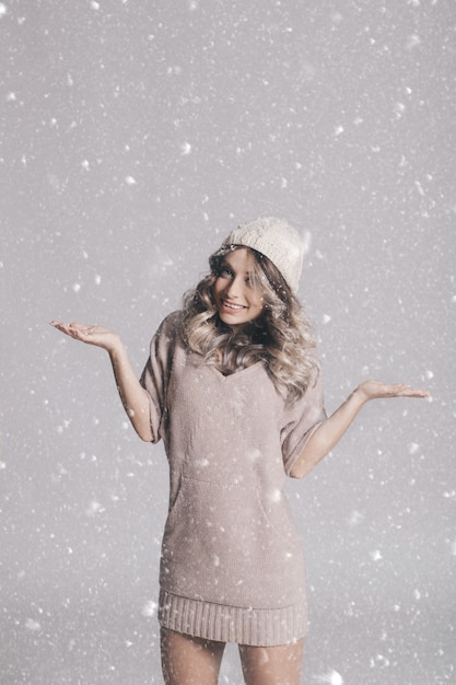 Free photo beautiful portrait of young attractive woman in knitted clothes on snowy background