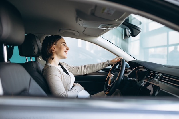 Beautiful pregnant woman driving in car