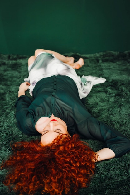 Free Photo beautiful red-haired woman lies on a green blanket