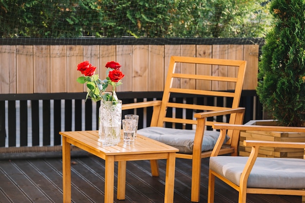 Beautiful red rose vase and drink on wooden table at rooftop