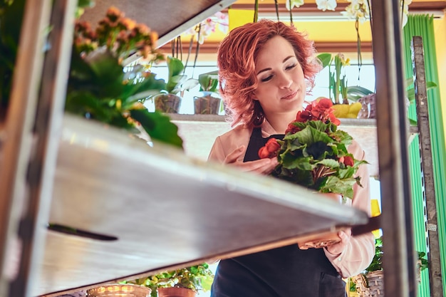 Free Photo beautiful redhead female florist wearing uniform working in a flower shop.