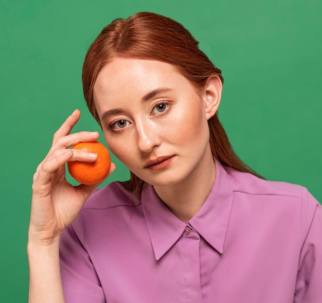 Free photo beautiful redhead woman posing with oranges