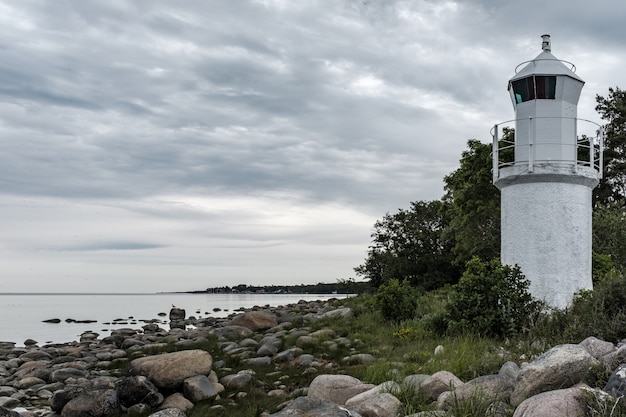 beautiful rocky coast of the sea with a white lighthouse tower on the side